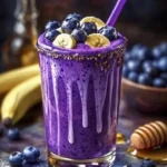 Banana-blueberry smoothie in a glass topped with fresh blueberries