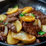 A delicious beef and potato stir fry served in a skillet with vibrant vegetables.