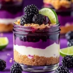 Individual jars of blackberry lime cheesecake topped with fresh blackberries and lime zest.