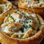 Garlic bread bowl filled with creamy chicken alfredo pasta.