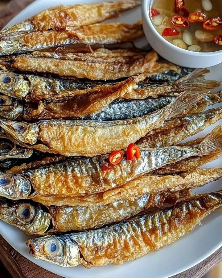 Plate of crispy fried dried fish garnished with herbs.