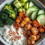 Glazed chicken rice bowl with broccoli and cucumber on a plate