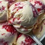 Bowl of homemade strawberry vanilla bean ice cream topped with fresh strawberries