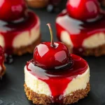 Mini cherry cheesecakes topped with fresh cherries on a white plate