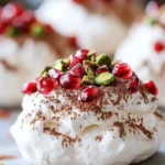 Mini Pavlovas topped with pomegranate seeds and pistachios on a dessert plate