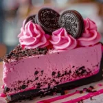 Pink Velvet Oreo Cheesecake topped with crushed Oreos and pink cream frosting.
