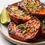 Roasted sweet potato steaks drizzled with gochujang-maple glaze on a plate.